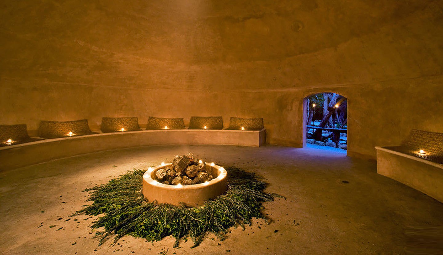 Interior de un temazcal con hierbas y luz cálida